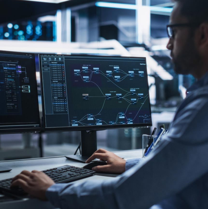 Engineer coding in front of dual monitors