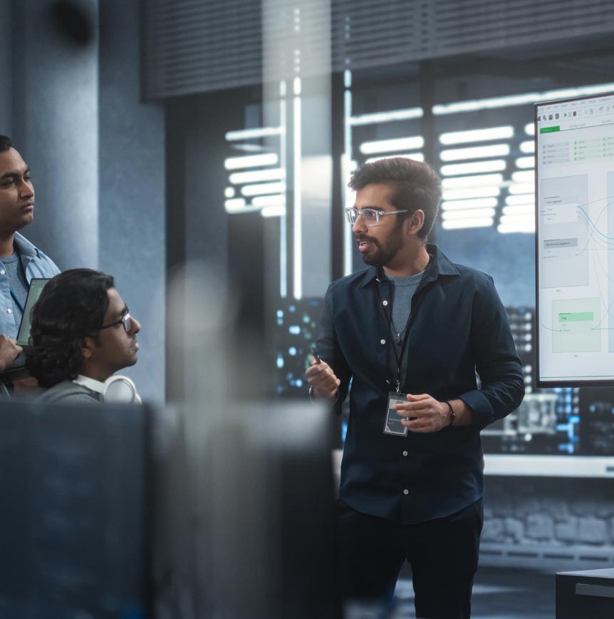 IT Team in a modern office setting engaged in a presentation with diagrams and data on a large screen, representing collaborative IT operations and smart infrastructure solutions for government systems