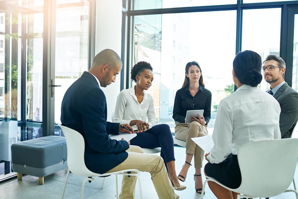 A group of professionals seated in a circle discussing data strategy and innovation in healthcare