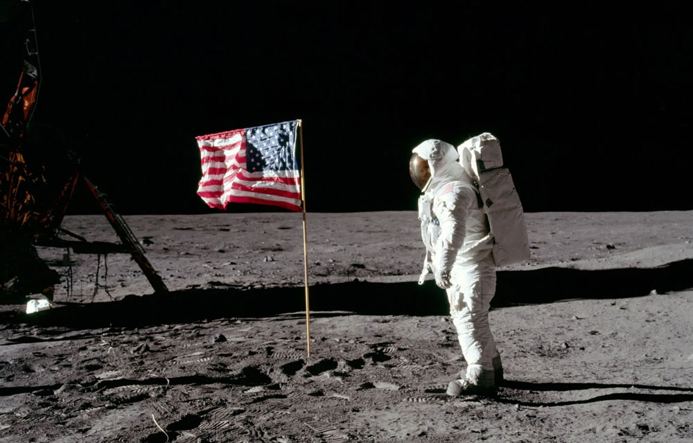 Neil Armstrong standing next to the US flag on the Moon.