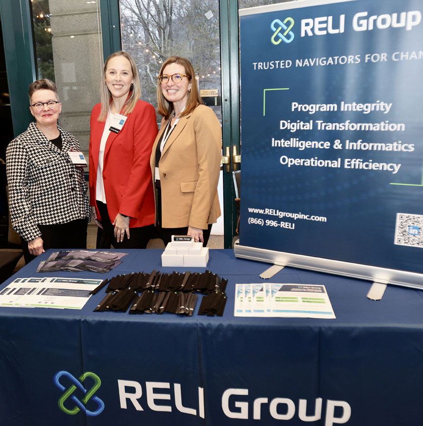 RELI Group employees at a government event standing in conference booth