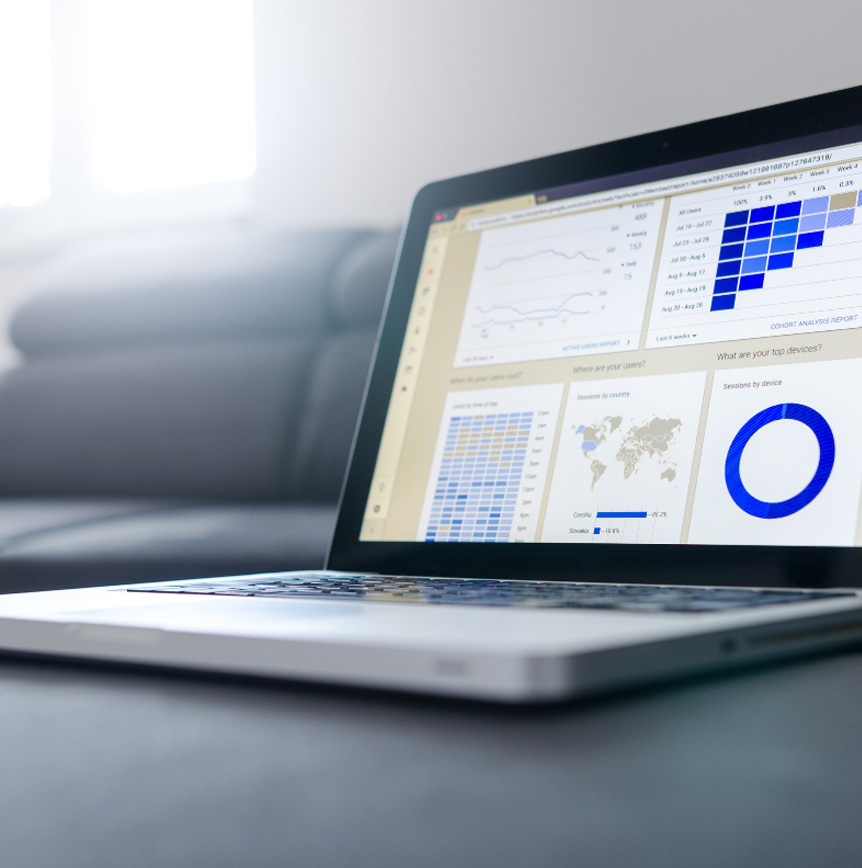 RELI Group laptop displaying analytics dashboard with blue graphs, line charts and tables
