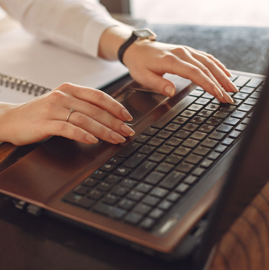 Close-up of hands typing on a computer keyboard beside a notebook, representing digital content creation, information management, and AI readiness.