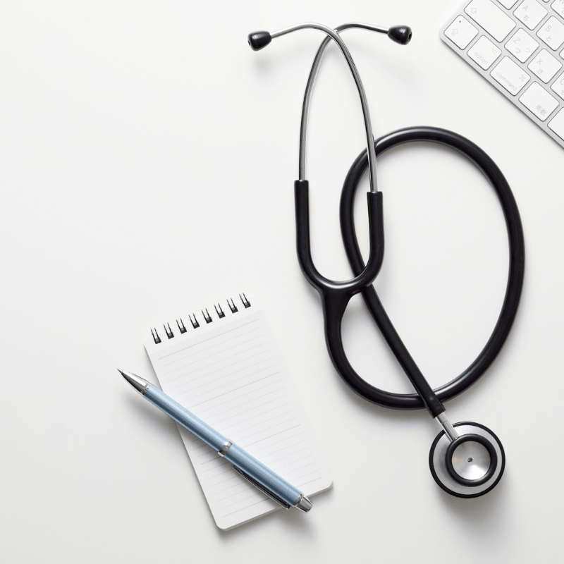Stethoscope beside a notepad, pen and keyboard representing preparation for the FY 2027 ICD-10-CM update.