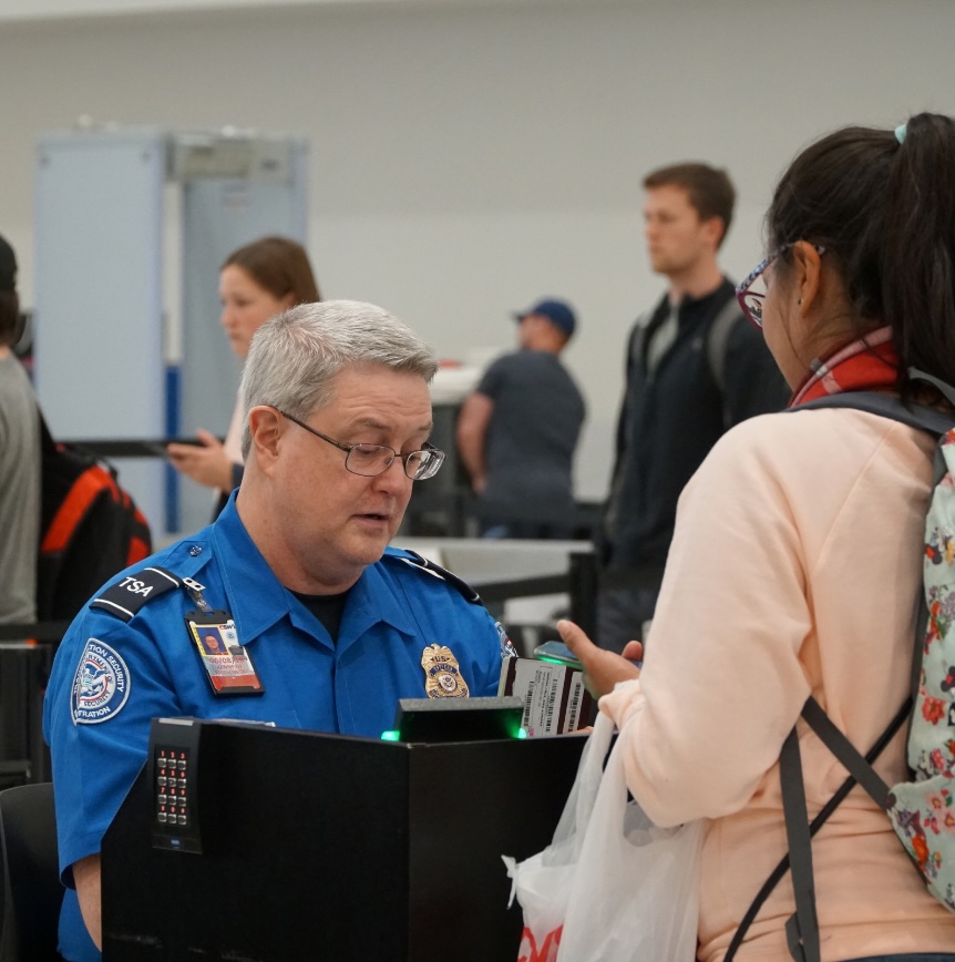 TSA officer assisting a traveler at an airport security screening checkpoint